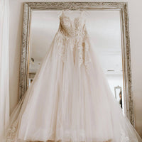 Robe de mariée élégante avec broderies, accrochée devant un miroir, idéale pour le jour J.