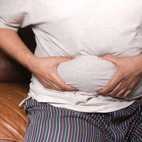 Homme touchant son ventre pour illustrer le besoin d'utiliser des sous-vêtements amincissants.