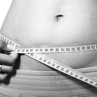 Femme mesurant son tour de taille avec un mètre ruban, symbolisant la perte de ventre sans sport.