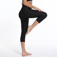 Femme portant des leggings anti-cellulite noirs, debout sur une jambe, montrant un look tendance.