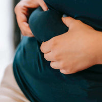 Personne tenant son ventre, illustrant l'impact du stress sur la prise de poids.