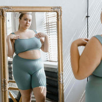 Femme regardant son reflet dans un miroir, explorant l'acceptation de son corps avec confiance.